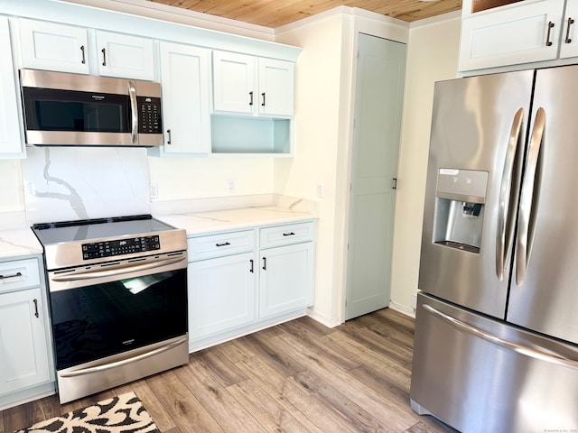 kitchen with light wood-style floors, light stone counters, stainless steel appliances, and white cabinetry