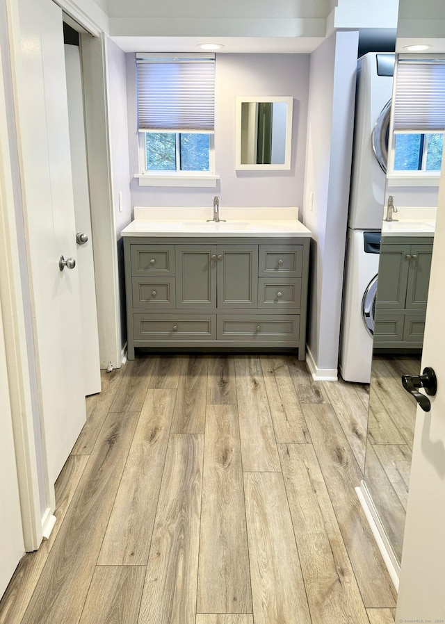 full bath featuring vanity, baseboards, stacked washer and dryer, and hardwood / wood-style floors