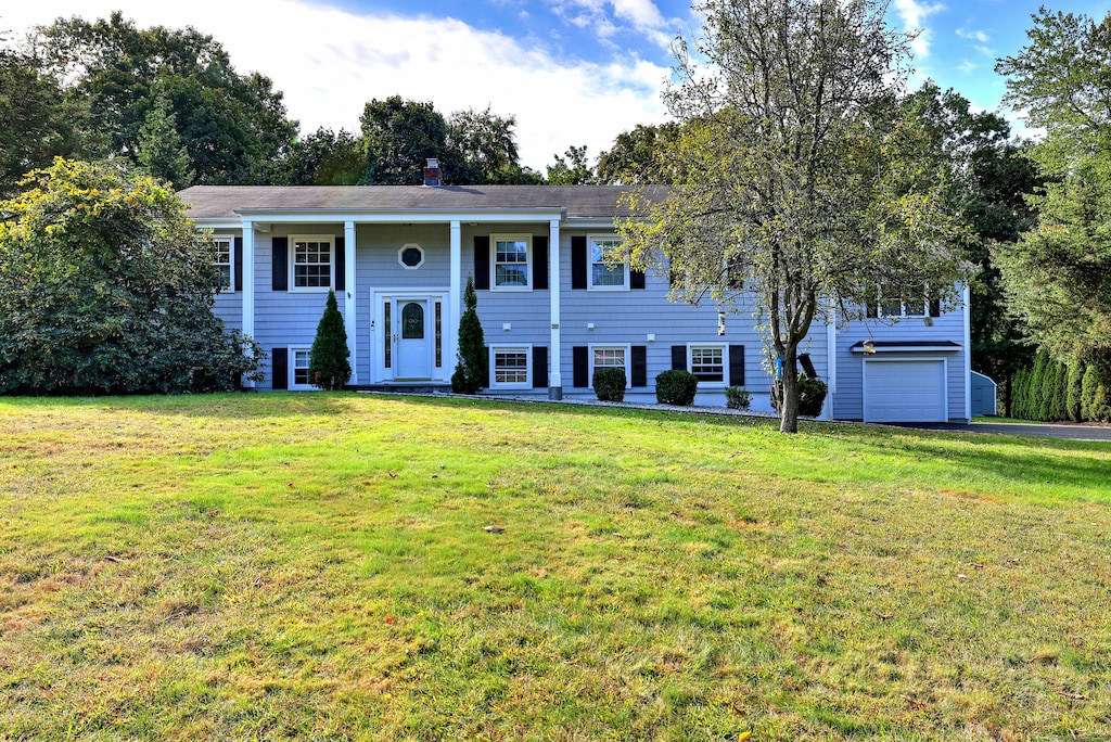 raised ranch featuring a front lawn and a garage