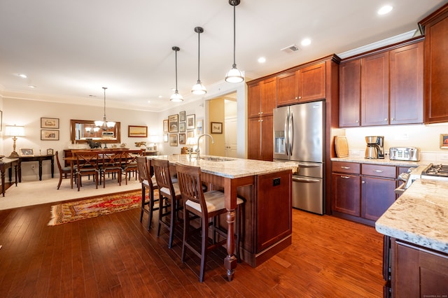 kitchen featuring appliances with stainless steel finishes, dark hardwood / wood-style floors, a kitchen island with sink, and pendant lighting