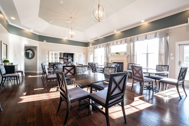 dining space with a chandelier, dark hardwood / wood-style floors, a towering ceiling, and a raised ceiling