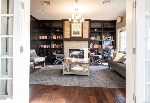 living room featuring an inviting chandelier, a large fireplace, and dark wood-type flooring