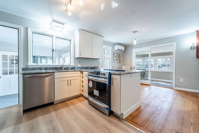 kitchen featuring stainless steel appliances, kitchen peninsula, a wall unit AC, and white cabinets