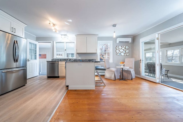 kitchen featuring light hardwood / wood-style floors, a wall mounted air conditioner, white cabinets, and stainless steel appliances