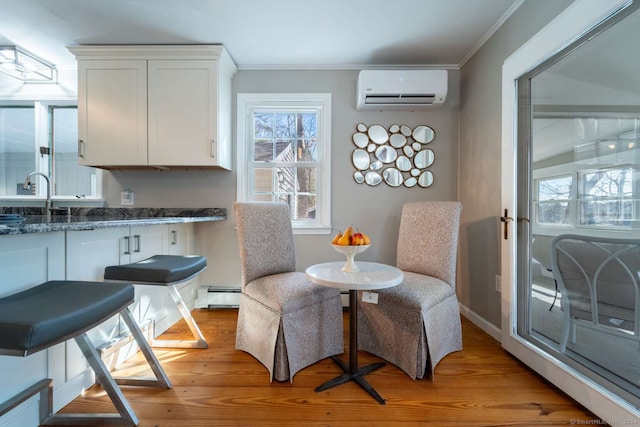 dining area with sink, a baseboard heating unit, light hardwood / wood-style floors, a wall unit AC, and ornamental molding