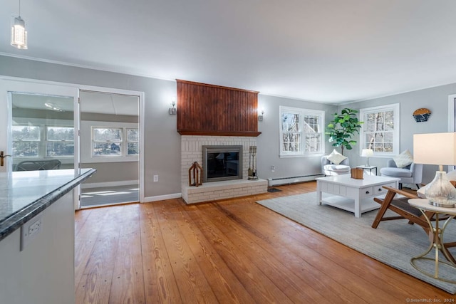 unfurnished living room with a brick fireplace, a healthy amount of sunlight, a baseboard radiator, and light wood-type flooring