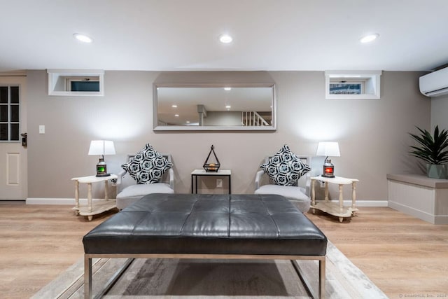 sitting room with an AC wall unit and light hardwood / wood-style flooring