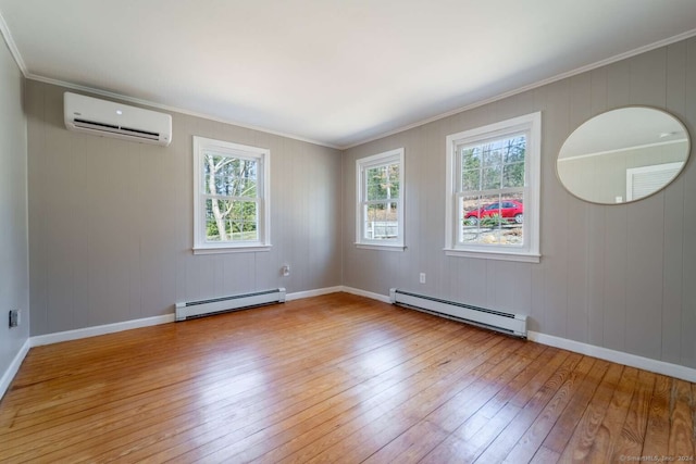 spare room featuring crown molding, a baseboard heating unit, light wood-type flooring, and a wall unit AC