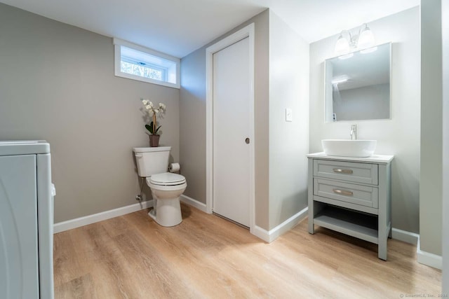 bathroom with toilet, hardwood / wood-style floors, vanity, and washer / clothes dryer