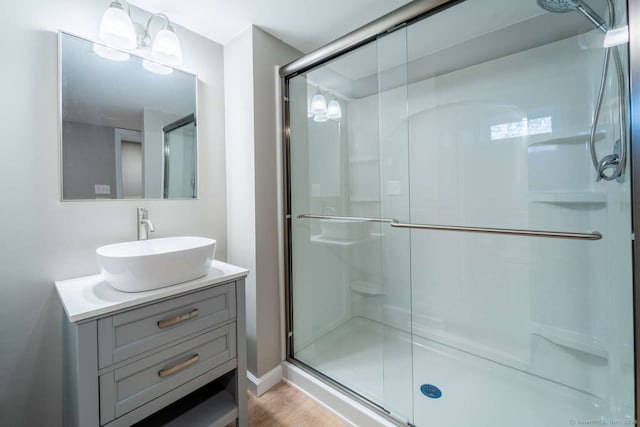 bathroom with a shower with door, vanity, and hardwood / wood-style flooring