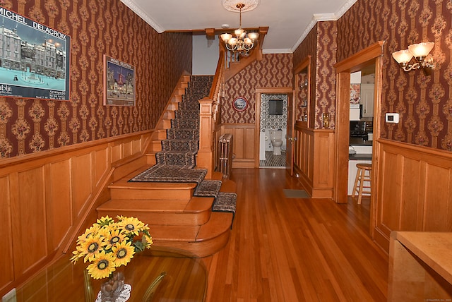 interior space featuring crown molding, wood-type flooring, and a chandelier