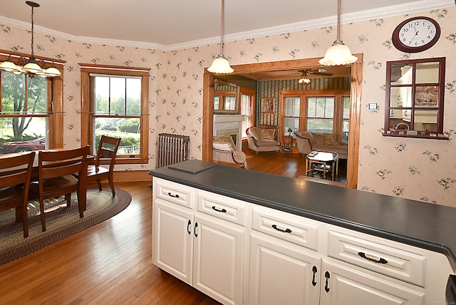 kitchen featuring crown molding, hardwood / wood-style floors, and hanging light fixtures