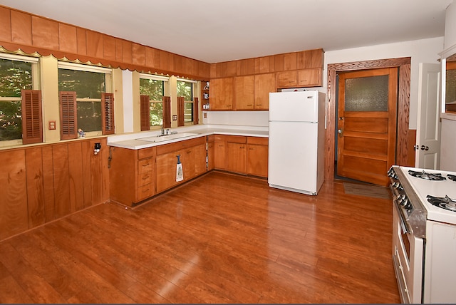 kitchen featuring white appliances, hardwood / wood-style flooring, and sink