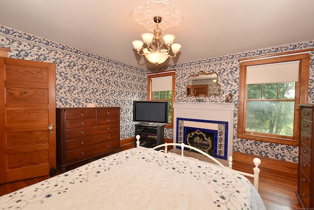 unfurnished bedroom featuring a chandelier, wood-type flooring, and a tile fireplace