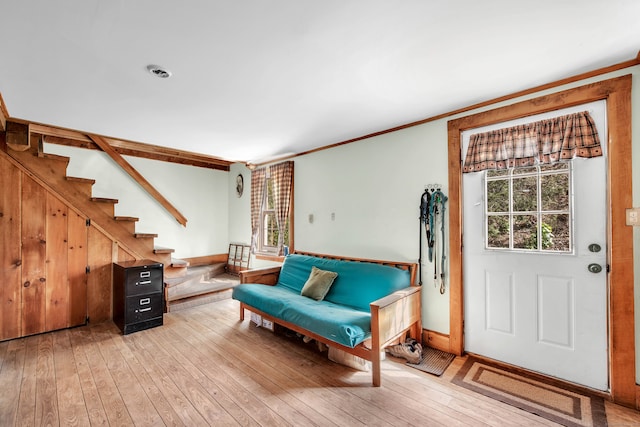 living area featuring a wealth of natural light, crown molding, and light hardwood / wood-style floors