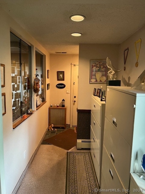 corridor featuring a textured ceiling, dark colored carpet, and washing machine and clothes dryer