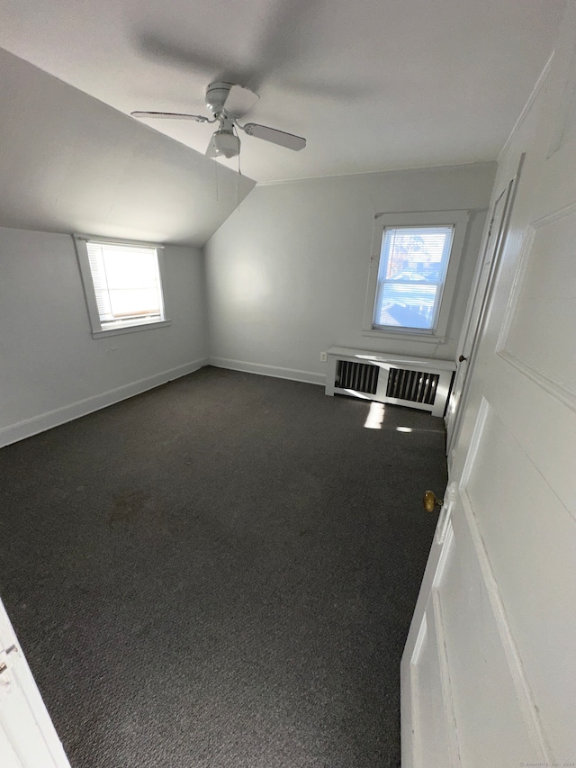 bonus room with vaulted ceiling, dark colored carpet, and ceiling fan