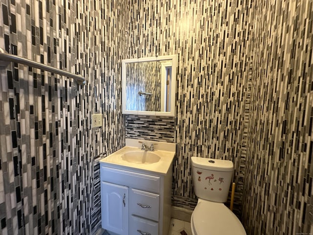 bathroom with vanity, decorative backsplash, tile walls, and toilet