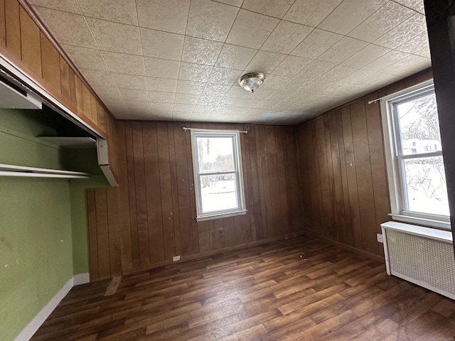 interior space with wooden walls, dark hardwood / wood-style floors, and radiator