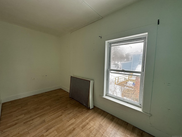 spare room with plenty of natural light, radiator, and light wood-type flooring