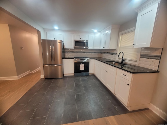 kitchen featuring sink, appliances with stainless steel finishes, white cabinetry, backsplash, and dark hardwood / wood-style floors