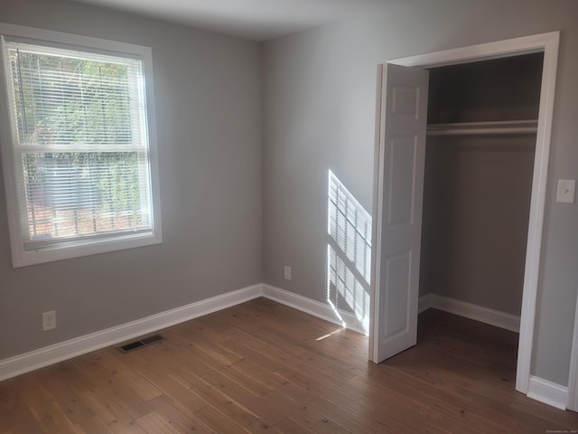 unfurnished bedroom with dark hardwood / wood-style flooring and a closet