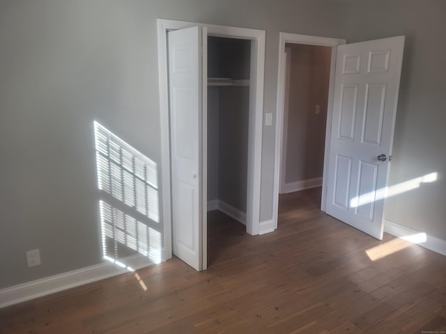 unfurnished bedroom with dark hardwood / wood-style floors and a closet