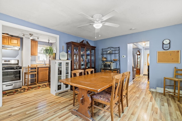 dining room with ceiling fan, sink, and light wood-type flooring