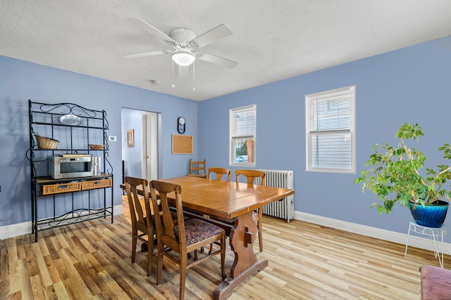 dining space with ceiling fan, a textured ceiling, radiator, and light hardwood / wood-style flooring