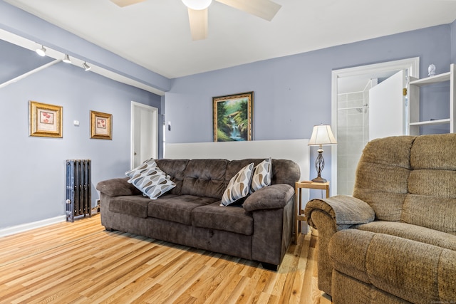 living room featuring track lighting, light hardwood / wood-style flooring, radiator, and ceiling fan