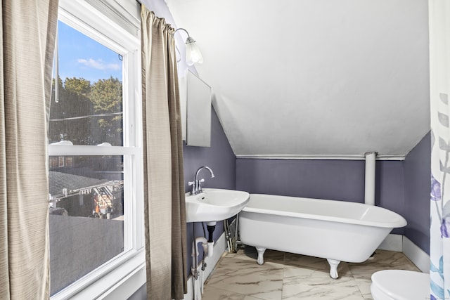 bathroom featuring toilet, a tub to relax in, and vaulted ceiling