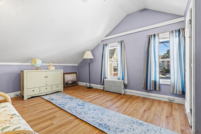 bedroom with radiator, light hardwood / wood-style floors, and vaulted ceiling