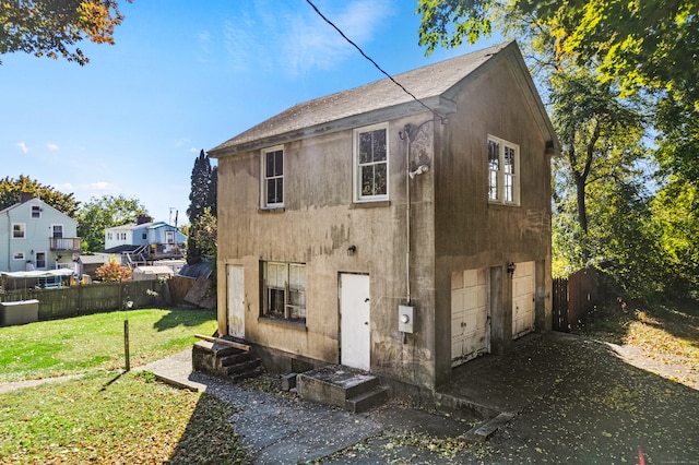 rear view of property featuring a garage and a yard