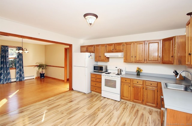 kitchen featuring white appliances, sink, light hardwood / wood-style flooring, a chandelier, and hanging light fixtures