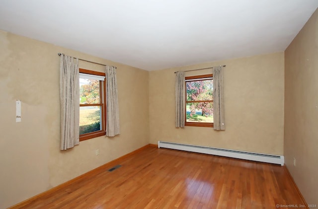 spare room with a baseboard radiator and hardwood / wood-style flooring