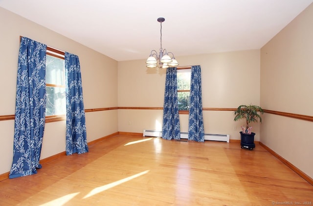 empty room with hardwood / wood-style floors, baseboard heating, and an inviting chandelier