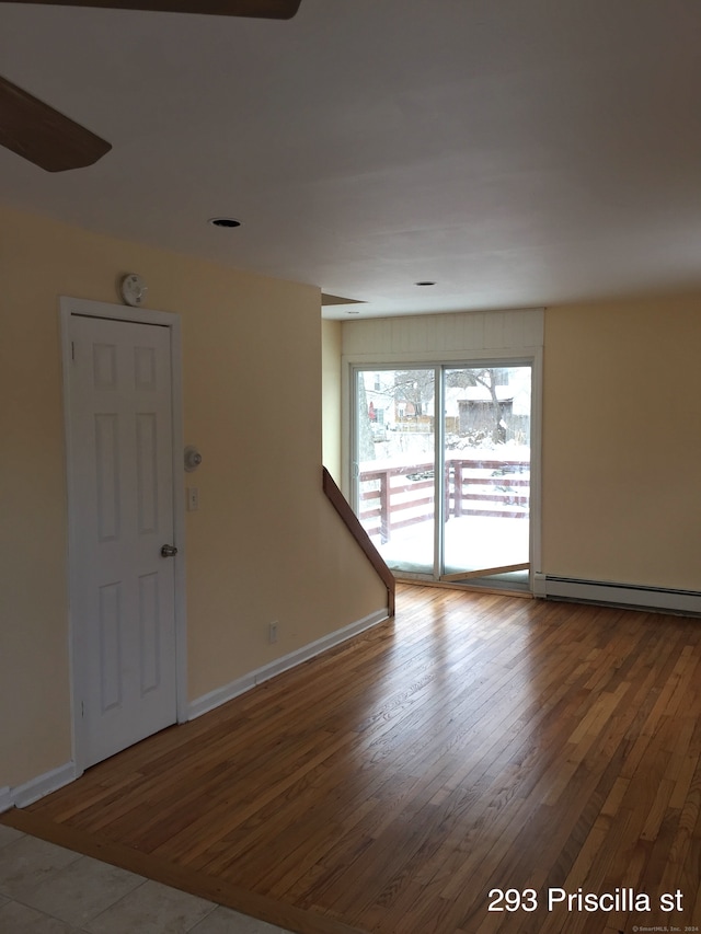 spare room featuring hardwood / wood-style flooring and a baseboard heating unit