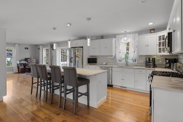 kitchen featuring appliances with stainless steel finishes, plenty of natural light, a kitchen island, and white cabinets