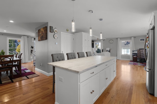 kitchen featuring white cabinetry, a center island, a breakfast bar, and a wealth of natural light