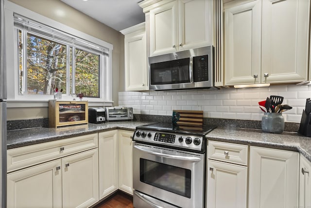 kitchen featuring decorative backsplash, dark stone counters, and appliances with stainless steel finishes