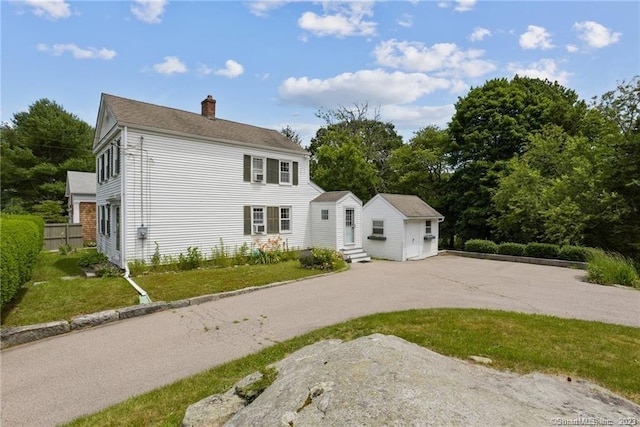 colonial house featuring a front lawn, an outdoor structure, and a garage