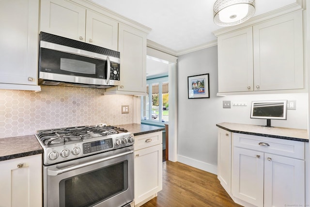 kitchen with tasteful backsplash, appliances with stainless steel finishes, dark countertops, and crown molding