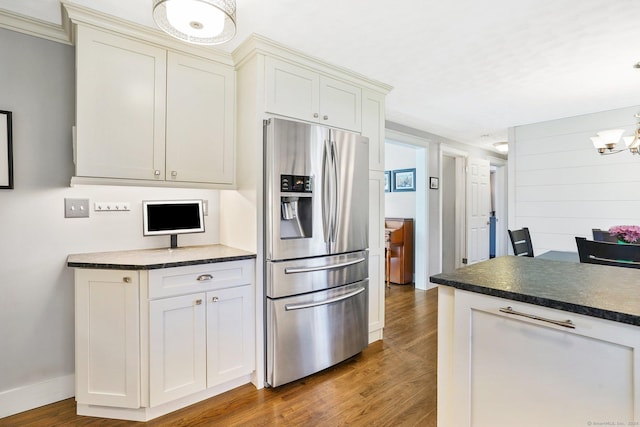 kitchen featuring a chandelier, stainless steel fridge with ice dispenser, dark countertops, wood finished floors, and white cabinetry