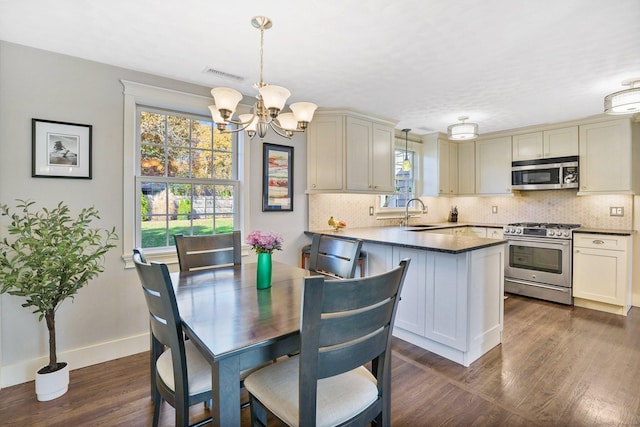 dining area with dark wood-style floors, visible vents, a wealth of natural light, and an inviting chandelier