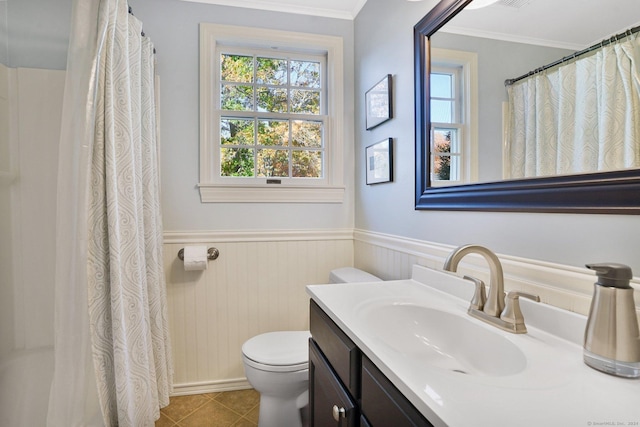 full bath featuring crown molding, toilet, wainscoting, vanity, and tile patterned flooring