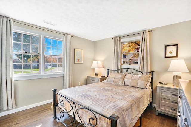 bedroom featuring visible vents, baseboards, and dark wood-style flooring