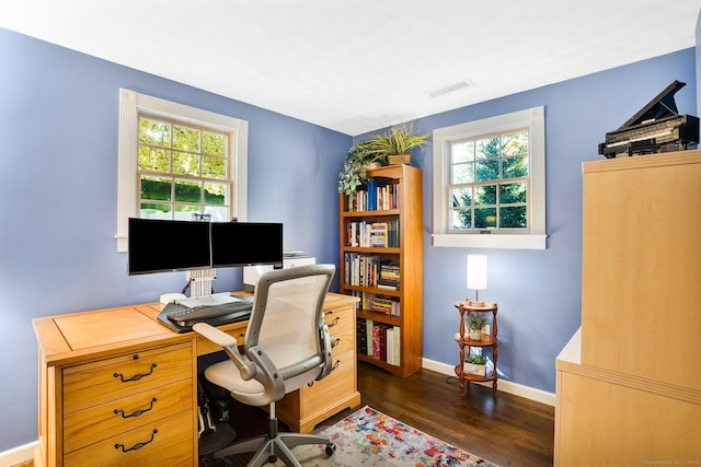 office space with dark wood-style floors, a healthy amount of sunlight, visible vents, and baseboards