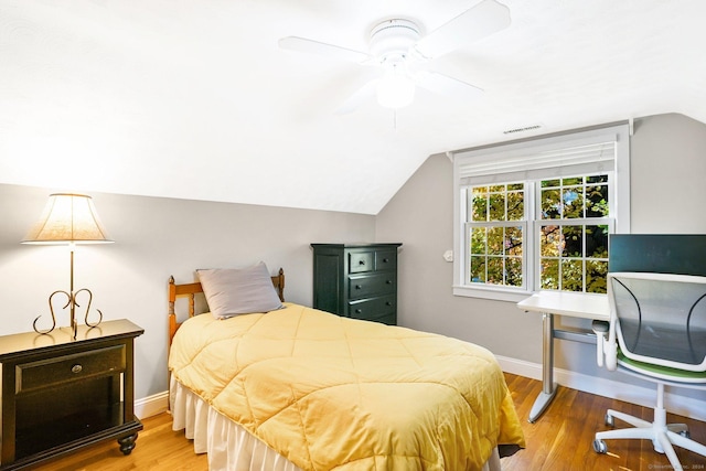 bedroom featuring wood finished floors, a ceiling fan, visible vents, vaulted ceiling, and baseboards