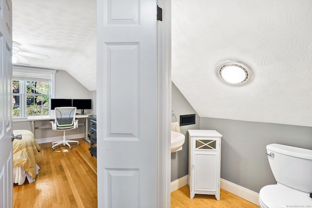 half bathroom with baseboards, toilet, wood finished floors, vaulted ceiling, and a textured ceiling