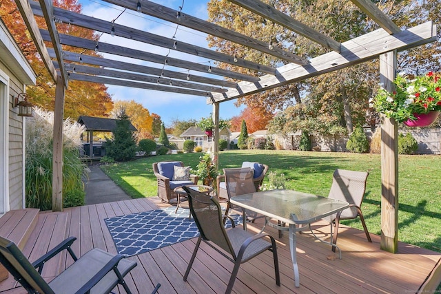 deck featuring a yard, outdoor dining space, fence, a pergola, and an outdoor structure